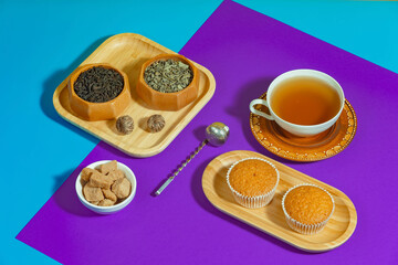 Tea in a cup in a composition with pastries and dessert, on a bright colored background.