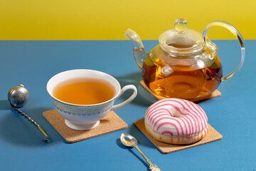 Tea in a cup in a composition with pastries and dessert, on a bright colored background.