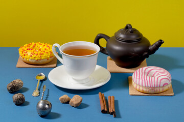 Fototapeta premium Tea in a cup in a composition with pastries and dessert, on a bright colored background.