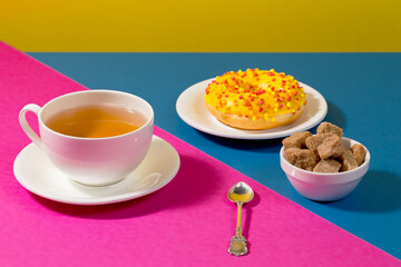 Tea in a cup in a composition with pastries and dessert, on a bright colored background.