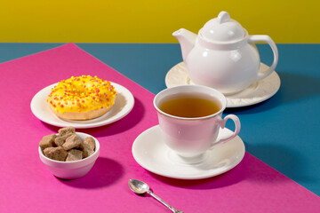 Tea in a cup in a composition with pastries and dessert, on a bright colored background.