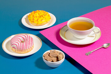 Tea in a cup in a composition with pastries and dessert, on a bright colored background.