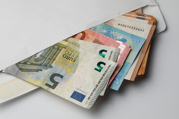 Closeup with envelope full of Euro banknotes on white background