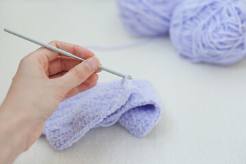 Hand crocheting with pastel soft fluffy purple lilac yarn - hobby and handmade things closeup