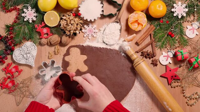 Female hands squeeze christmas cookies out of the dough on the background of a festively decorated table, top view