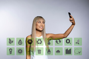 Blond woman taking selfie through mobile phone with sustainable icons against white background
