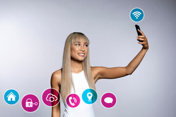 Happy woman taking selfie through smart phone with icons on white background