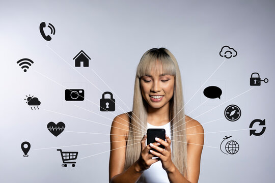 Smiling young woman using mobile phone with icons over white background