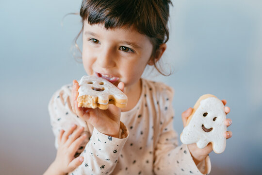Little girl eating homemade halloween ghost cookies