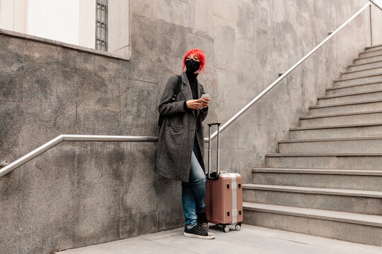Redheaded woman waiting with luggage by steps