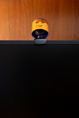 External round black web camera with a smiling cap on a black monitor. Smiling cover for a webcam. Protection against spying.
