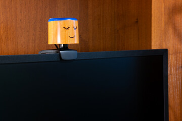 External round black web camera with a smiling cap on a black monitor. Smiling cover for a webcam. Protection against spying.