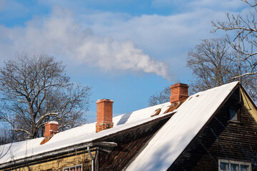 Smoky house chimney on a cold, sunny, snowy winter morning