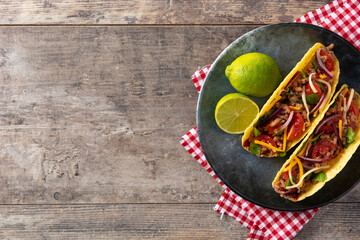 Traditional Mexican tacos with meat and vegetables on wooden table. Top view. Copy space