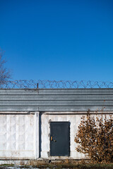 A black abandoned metal door in the white concrete wall