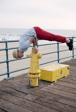 Man balancing on fire hydrant by railing at Santa Monica pier