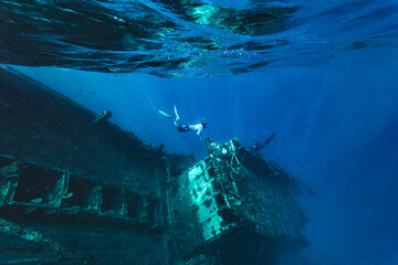 Man swimming underwater near abandoned ship in sea