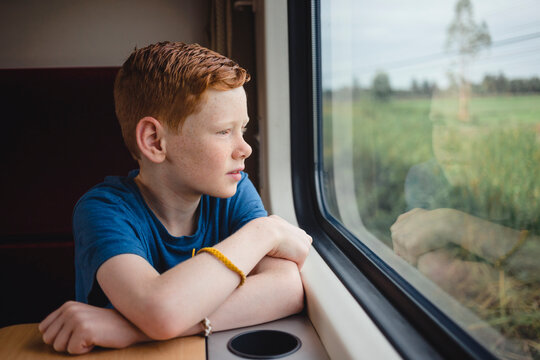 Boy looking through window while traveling in train, Thailand, Asia