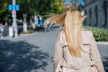Fototapeta premium a beautiful blonde woman in an autumn raincoat walks outside