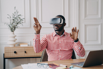 Concentrated Afro american businessman using VR headset, experiencing virtual reality playing game - Powered by Adobe