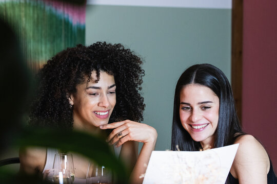 Smiling friends reading menu at restaurant