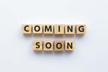 Text COMING SOON on wooden cubes on white background. Square wood blocks. Top view, flat lay.