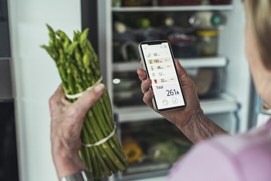 Woman calculating food calories through smart phone at home