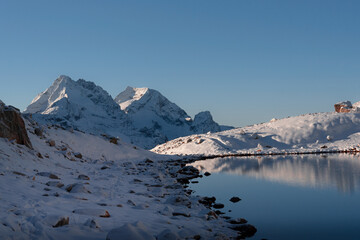 A high mountain lake in the early morning in winter with mountains in the snow