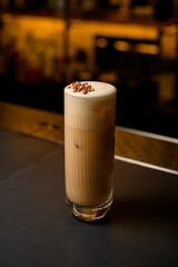 Close-up of tall glass with whipped creamy cocktail drink on the bar counter