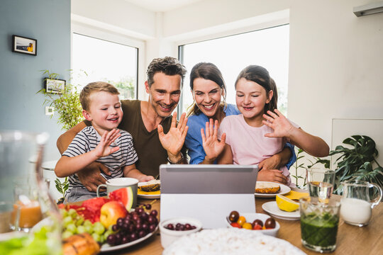 Family greeting while doing video call on digital tablet at home