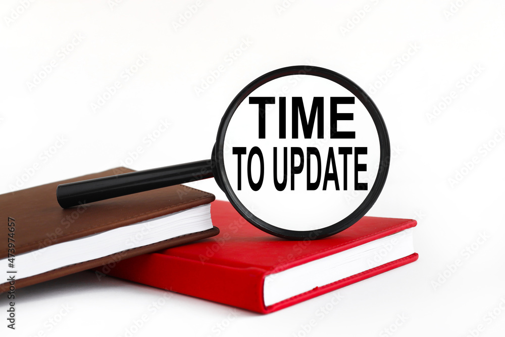 Poster time to update. white background text on magnifying glass. magnifying glass on brown and red noteboo