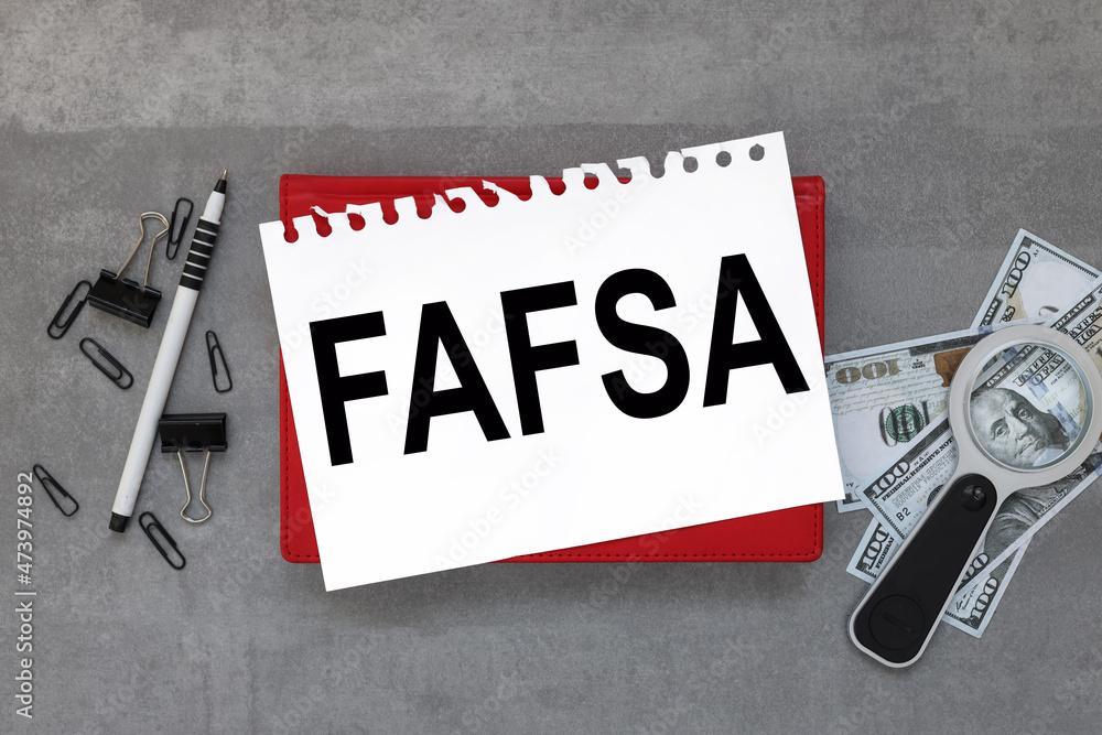 Poster fafsa. on the desktop there is a red notebook, reports, a white sheet of paper with a place to inser