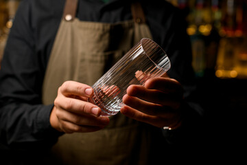 Close-up view of empty transparent tall cocktail glass in male hands