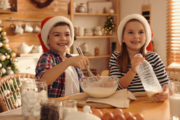 Cute little children making dough for Christmas cookies at home