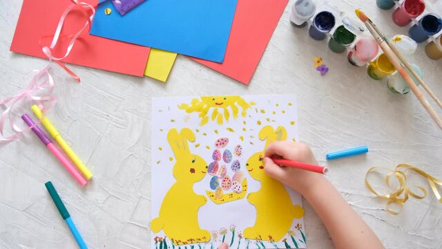 Child making card with Easter bunnies  from colorful paper. Applique. Handmade. Project of children's creativity, handicrafts, crafts for kids.