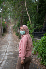 a woman wearing a hijab wearing a mask is walking in the forest