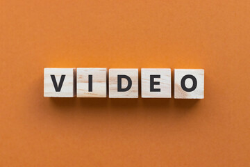 Text VIDEO on wooden cubes on orange background. Wood blocks. Top view, flat lay.