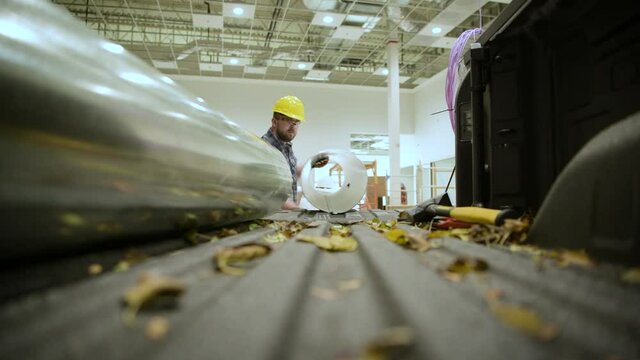 Worker Unloading Pieces of HVAC Metal Air Duct Fron His Pickup Truck
