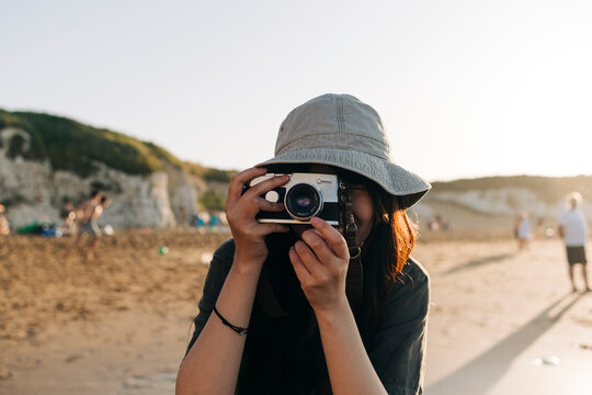 Young woman photographing through camera at beach
