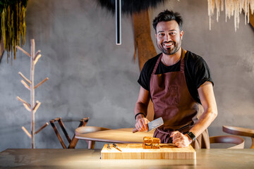 Smiling chef with meat cleaver standing by food in commercial kitchen
