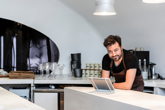 Confident chef standing by digital tablet in restaurant kitchen