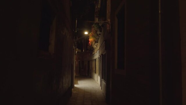 Pov walking through a dark empty alley during the night, spooky and frightening scene in Venice, Italy
