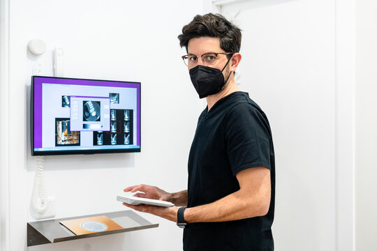 Male dentist wearing protective face mask holding computer keyboard in clinic