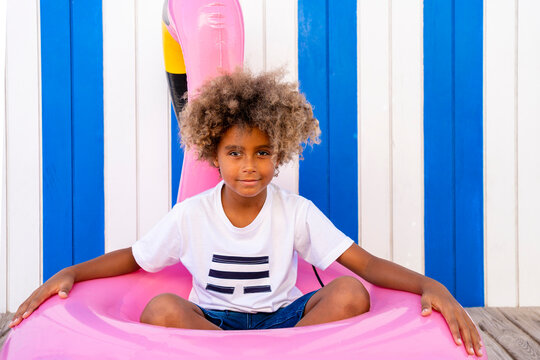 Boy sitting in inflatable flamingo in front of wall