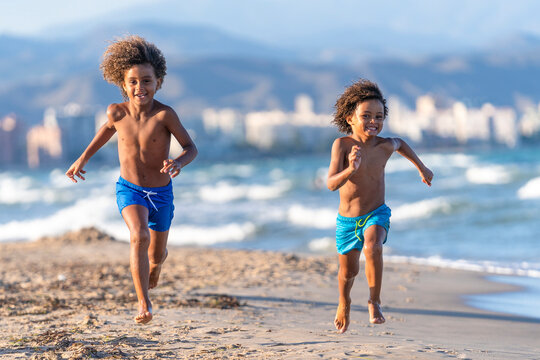 Cheerful brothers running together at beach