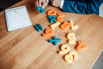 Senior businessman calculating with numbers toy by digital tablet in office