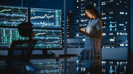 Financial Analyst Using Tablet Computer, Standing Next to Multi-Monitor Workstation with Real-Time...
