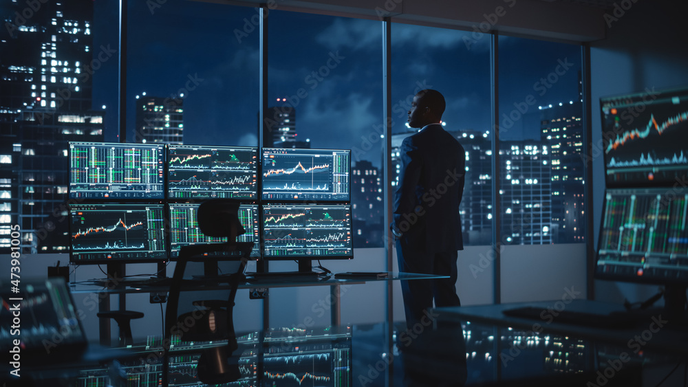 Aufkleber successful businessman looking out of the window on late evening. modern hedge fund office with comp