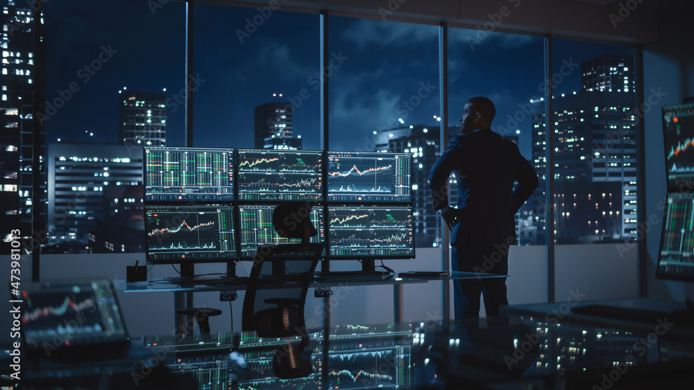 Aufkleber successful businessman looking out of the window on late evening. modern hedge fund office with comp