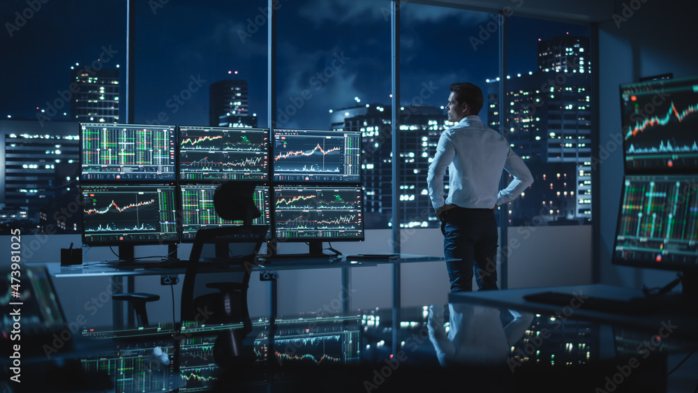 Aufkleber successful businessman looking out of the window on late evening. modern hedge fund office with comp